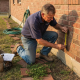 Worker inspecting Texas house foundation exterior
