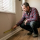 Homeowner measuring crack in living room wall